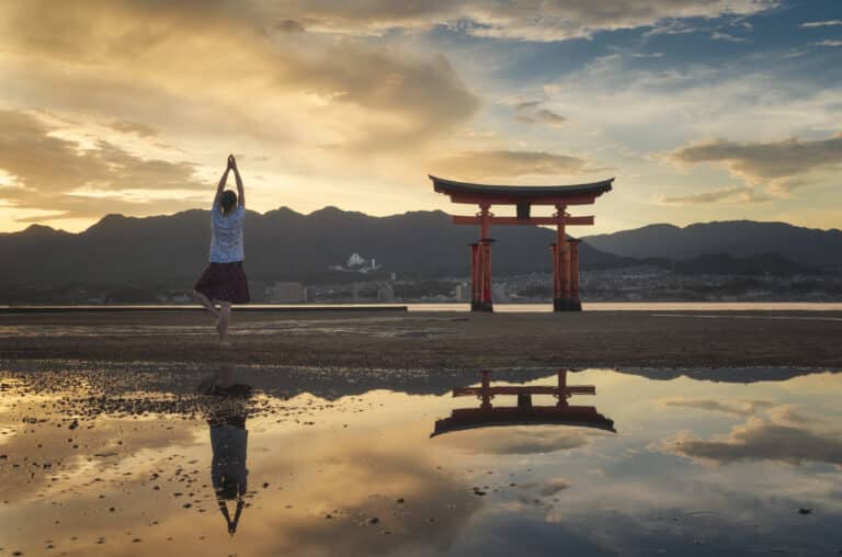 Mulher apreciando o pôr do sol na ilha de Itsukushima ou Miyajima, Hiroshima, Japão